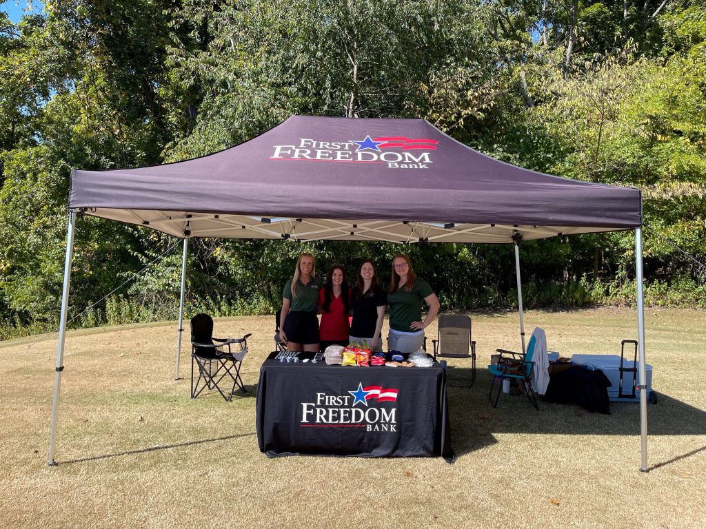 First Freedom Bank Staff Pose under a hospitality tent on the golf course. 